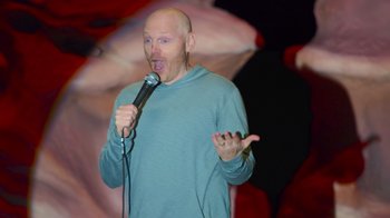 Movie still from “Bill Burr: Live at Red Rocks” (2022), directed by Mike Binder – A bald man is holding a microphone up to his mouth; Medium shot, High angle
