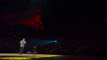 Movie still from “Bill Burr: Live at Red Rocks” (2022), directed by Mike Binder – A man standing on a stage in front of an audience; Extreme Wide shot, High angle
