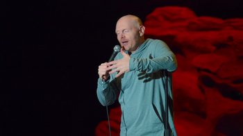 Movie still from “Bill Burr: Live at Red Rocks” (2022), directed by Mike Binder – A bald man is holding a microphone in his hands; Medium shot, High angle