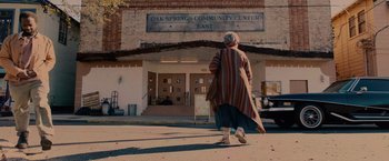 An older woman walking down the sidewalk in front of a building