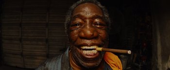 An older man with a wooden stick in his mouth