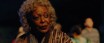 An older woman with curly blonde hair wearing a striped shirt