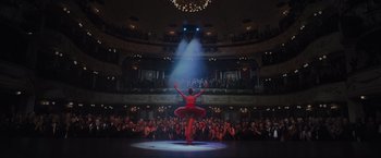 A woman in a red dress is on a stage in front of an audience
