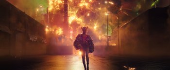 Movie still from “Birds of Prey” (2020), directed by Cathy Yan – A woman walking down a street in front of an exploding building; Extreme Wide shot, Over the shoulder angle