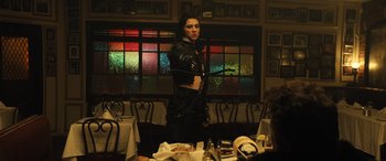 Movie still from “Birds of Prey” (2020), directed by Cathy Yan – A woman standing in front of a bunch of tables; Medium shot, Over the shoulder angle