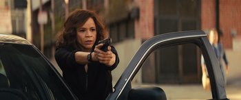 Movie still from “Birds of Prey” (2020), directed by Cathy Yan – A woman holding a gun while standing next to a car; Medium shot, Over the shoulder angle