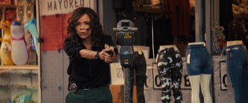 Movie still from “Birds of Prey” (2020), directed by Cathy Yan – A woman holding a gun in front of a parking meter; Medium shot, Over the shoulder angle