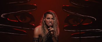 Movie still from “Birds of Prey” (2020), directed by Cathy Yan – A woman with dreadlocks is singing into a microphone; Close Up shot, High angle