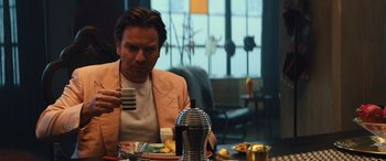 Movie still from “Birds of Prey” (2020), directed by Cathy Yan – A man sitting at a table with a cup of coffee; Medium shot, Over the shoulder angle