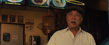 Movie still from “Birds of Prey” (2020), directed by Cathy Yan – An older man wearing a hat standing in front of a menu; Medium shot, Low angle