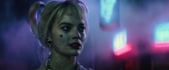 Movie still from “Birds of Prey” (2020), directed by Cathy Yan – A woman with makeup on her face is standing in a dark room; Close Up shot, Over the shoulder angle