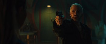 Movie still from “Birds of Prey” (2020), directed by Cathy Yan – A man holding a gun while standing in a room; Medium shot, Low angle