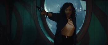 Movie still from “Birds of Prey” (2020), directed by Cathy Yan – A woman holding a gun in front of a round window; Medium shot, Low angle