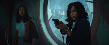 Movie still from “Birds of Prey” (2020), directed by Cathy Yan – A woman holding a gun while standing in front of a window; Medium shot, Over the shoulder angle