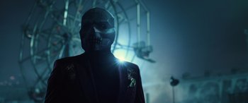 Movie still from “Birds of Prey” (2020), directed by Cathy Yan – A man in a suit and mask standing in front of a ferris wheel; Close Up shot, Low angle