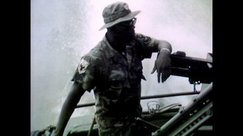 Movie still from “Bitchin': The Sound and Fury of Rick James” (2021), directed by Sacha Jenkins – A man in a hat and glasses is standing on a boat in the water; Medium shot, Low angle