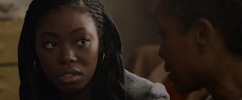 Movie still from “Black as Night” (2021), directed by Maritte Lee Go – A woman sitting next to another woman in front of a wall; Close Up shot, Over the shoulder angle