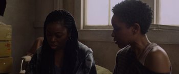 Movie still from “Black as Night” (2021), directed by Maritte Lee Go – Two women sitting on a couch talking to each other; Medium shot, Over the shoulder angle