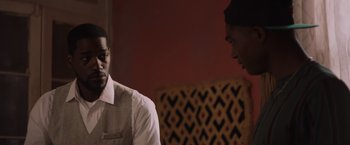 Movie still from “Black as Night” (2021), directed by Maritte Lee Go – Two men are talking to each other in a living room; Close Up shot, Over the shoulder angle