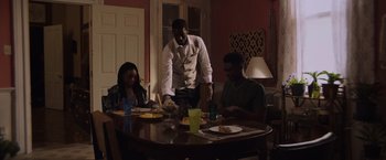 Movie still from “Black as Night” (2021), directed by Maritte Lee Go – Three people sitting at a table with plates of food; Medium shot, Over the shoulder angle