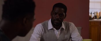 Movie still from “Black as Night” (2021), directed by Maritte Lee Go – A man in a white dress shirt and a gray vest; Close Up shot, Over the shoulder angle