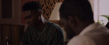 Movie still from “Black as Night” (2021), directed by Maritte Lee Go – Two young men sitting in front of each other in a room; Close Up shot, Over the shoulder angle
