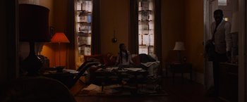 Movie still from “Black as Night” (2021), directed by Maritte Lee Go – A person sitting on a couch in a living room; Wide shot, High angle