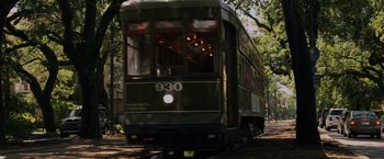 Movie still from “Black as Night” (2021), directed by Maritte Lee Go – A trolley car traveling down the tracks in a city; Extreme Wide shot, Low angle
