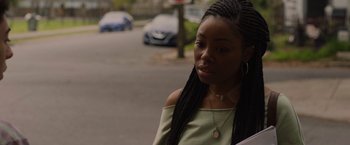 Movie still from “Black as Night” (2021), directed by Maritte Lee Go – A young woman with long black hair wearing a green top; Close Up shot, Over the shoulder angle