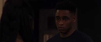 Movie still from “Black as Night” (2021), directed by Maritte Lee Go – A young man in a black shirt is looking at the camera; Close Up shot, Over the shoulder angle