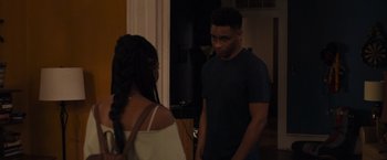 Movie still from “Black as Night” (2021), directed by Maritte Lee Go – A man and a woman standing next to each other in a room; Medium shot, Over the shoulder angle