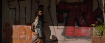 Movie still from “Black as Night” (2021), directed by Maritte Lee Go – A man and a woman walking down a street; Medium shot, Low angle