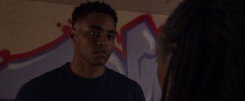 Movie still from “Black as Night” (2021), directed by Maritte Lee Go – A man standing in front of a wall with graffiti on it; Close Up shot, Over the shoulder angle