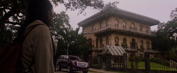 Movie still from “Black as Night” (2021), directed by Maritte Lee Go – A car is parked in front of a large house; Extreme Wide shot, Low angle