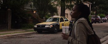 Movie still from “Black as Night” (2021), directed by Maritte Lee Go – A man walking down the street holding a coffee cup in front of a taxi cab; Extreme Wide shot, Low angle