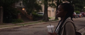 Movie still from “Black as Night” (2021), directed by Maritte Lee Go – A woman standing on the side of the road holding a drink; Close Up shot, Over the shoulder angle