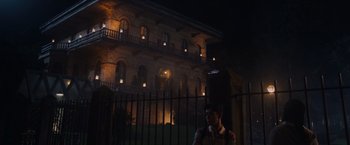 Movie still from “Black as Night” (2021), directed by Maritte Lee Go – A man standing in front of a building at night; Extreme Wide shot, Low angle