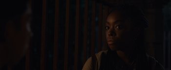 Movie still from “Black as Night” (2021), directed by Maritte Lee Go – A young black woman looking at the camera with her eyes wide open; Close Up shot, Over the shoulder angle