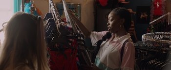 Movie still from “Black as Night” (2021), directed by Maritte Lee Go – A woman looking through a rack of clothes; Medium shot, Over the shoulder angle