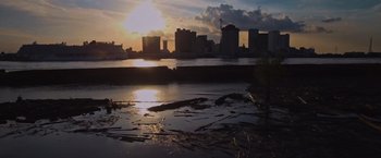 Movie still from “Black as Night” (2021), directed by Maritte Lee Go – The sun is setting over a body of water; Extreme Wide shot, Low angle