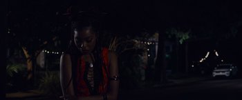 Movie still from “Black as Night” (2021), directed by Maritte Lee Go – A woman in an orange and black dress; Close Up shot, Over the shoulder angle