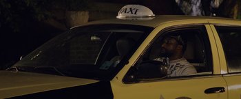 Movie still from “Black as Night” (2021), directed by Maritte Lee Go – A man sitting in the drivers seat of a yellow taxi cab; Close Up shot, Low angle