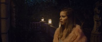 Movie still from “Black as Night” (2021), directed by Maritte Lee Go – A woman wearing a pink jacket standing in front of lights; Close Up shot, Over the shoulder angle