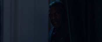 Movie still from “Black as Night” (2021), directed by Maritte Lee Go – A man in a suit and tie in a dark room; Close Up shot, Over the shoulder angle