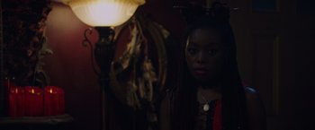 Movie still from “Black as Night” (2021), directed by Maritte Lee Go – A woman in a red and black dress and a lamp in the background; Close Up shot, Over the shoulder angle