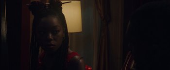 Movie still from “Black as Night” (2021), directed by Maritte Lee Go – A black woman with a red dress and a red bow in her hair; Close Up shot, Over the shoulder angle