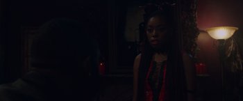Movie still from “Black as Night” (2021), directed by Maritte Lee Go – A woman in a black and red outfit standing in a dark room; Close Up shot, Over the shoulder angle