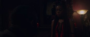 Movie still from “Black as Night” (2021), directed by Maritte Lee Go – A woman in a red and black dress looking at a cell phone; Medium shot, Over the shoulder angle