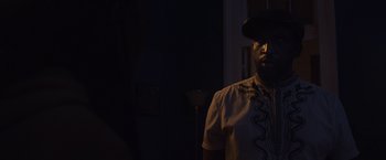 Movie still from “Black as Night” (2021), directed by Maritte Lee Go – A man in a hat is standing in the dark; Close Up shot, Over the shoulder angle