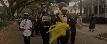 Movie still from “Black as Night” (2021), directed by Maritte Lee Go – A group of people marching down a street; Medium shot, Low angle
